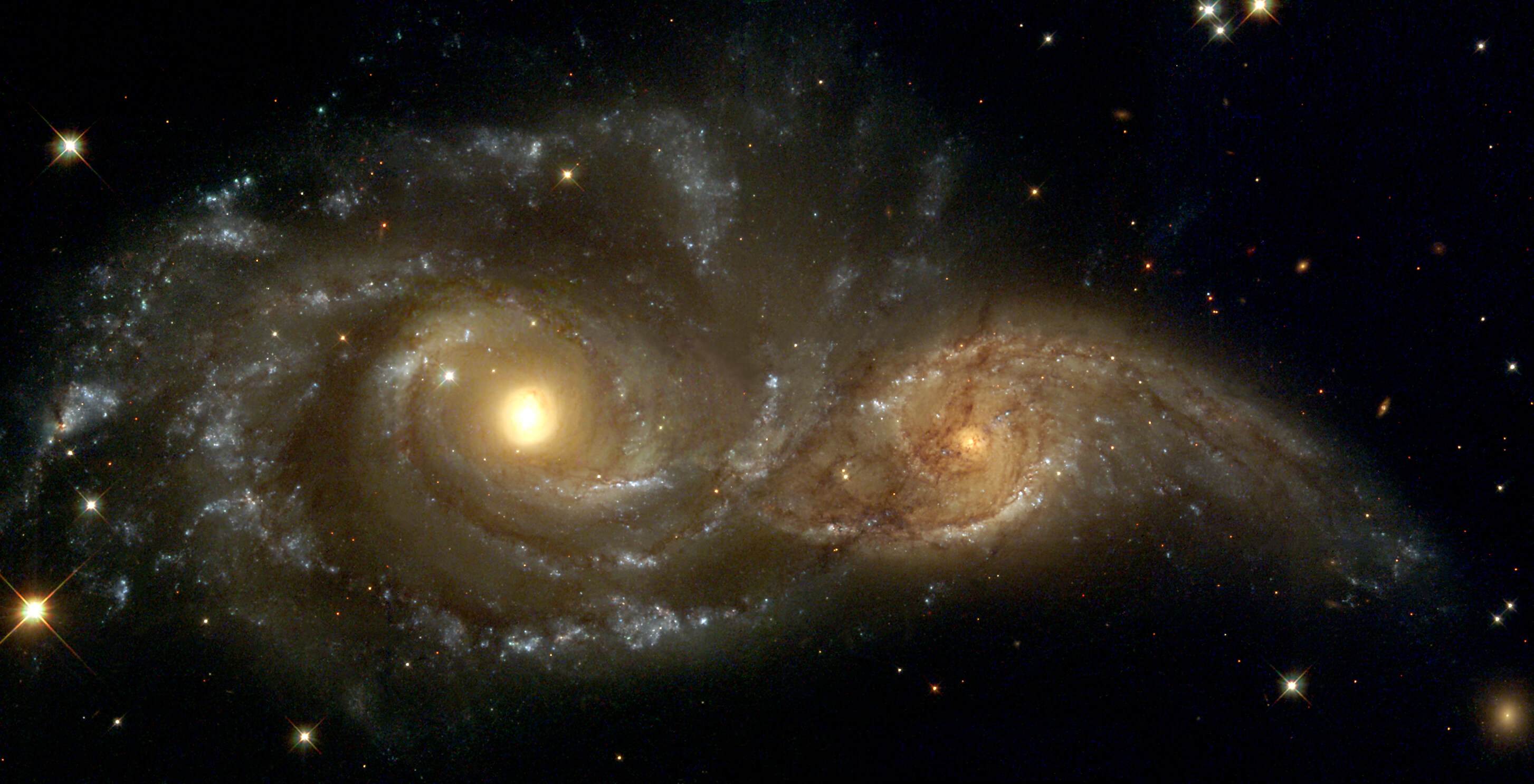 When galaxies collide or venture close to one another, gas and momentum is transferred between the galaxies. Shown are spiral galaxies NGC 2207 and IC 2163. Image: NASA and The Hubble Heritage Team.